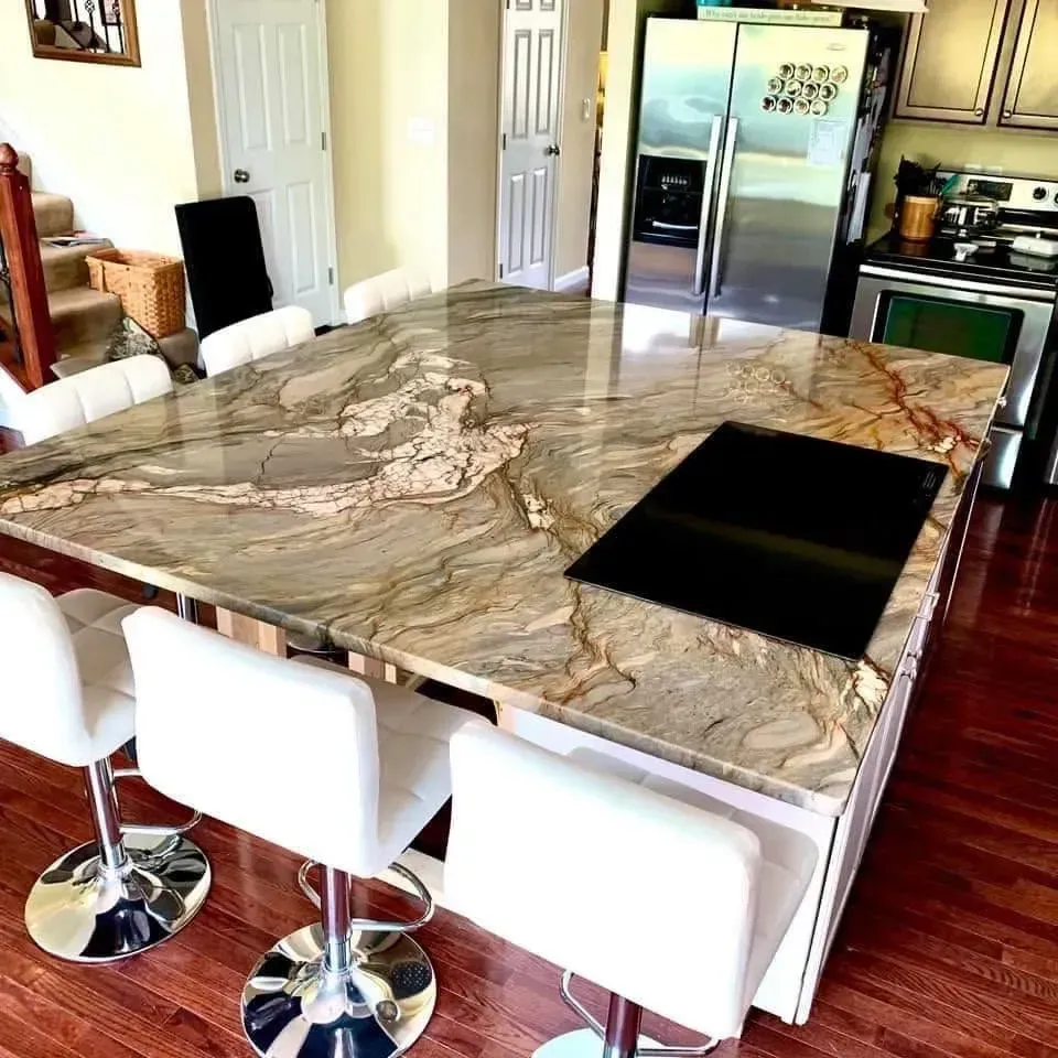 Kitchen island with granite countertop, built-in cooktop, and white bar stools on a hardwood floor.
