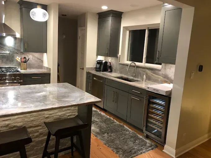 Modern kitchen with gray cabinets, granite countertops, and stainless steel appliances.