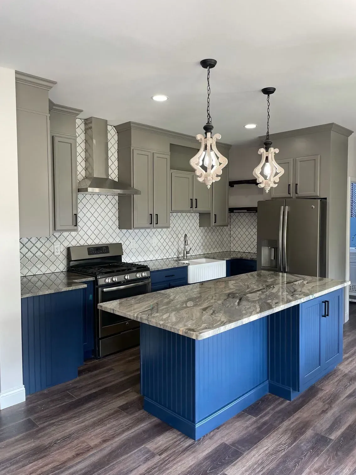 Modern kitchen with blue and gray cabinets, island, and two pendant lights.