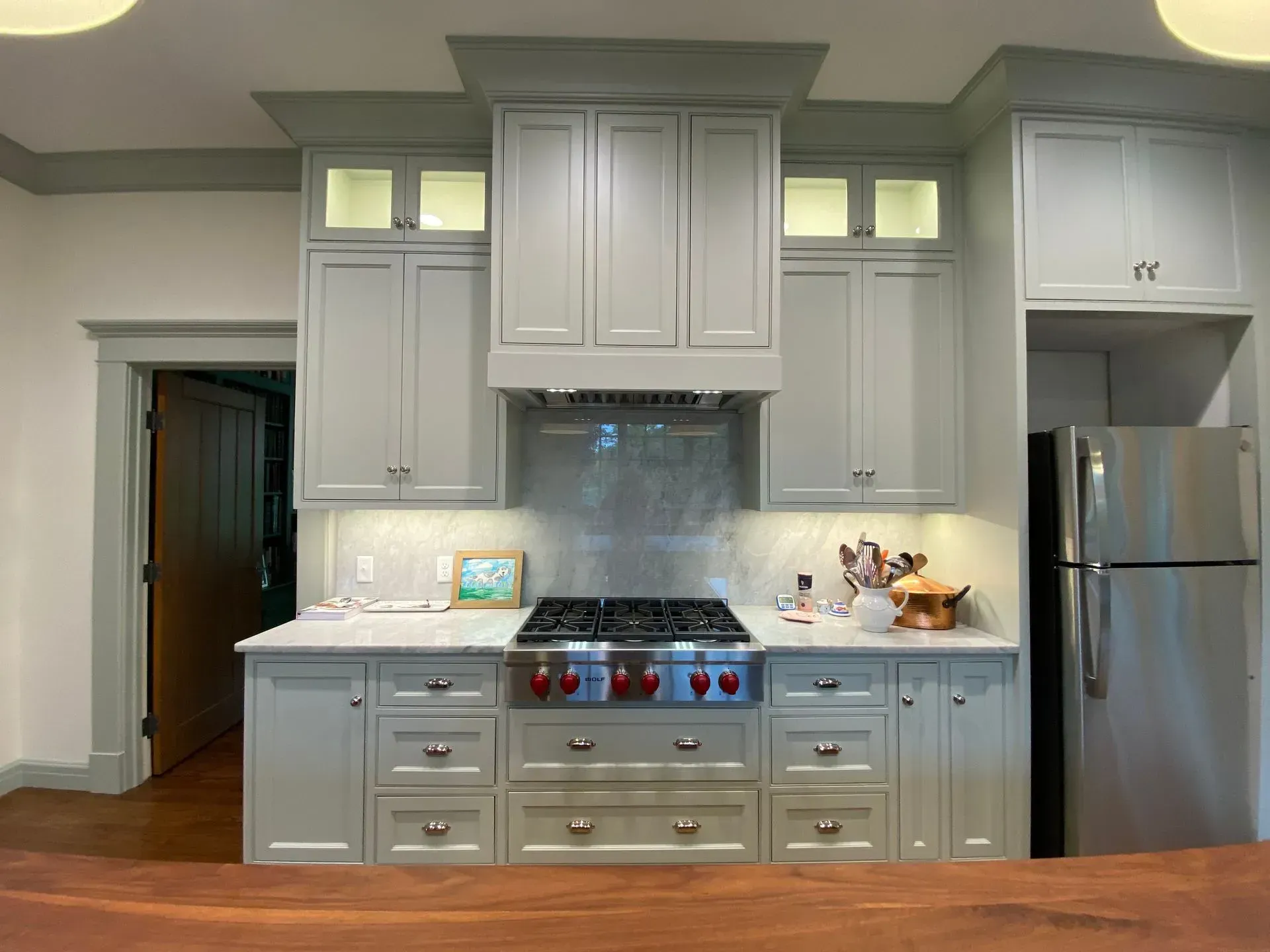 Gray kitchen cabinets with a stainless steel range and refrigerator.