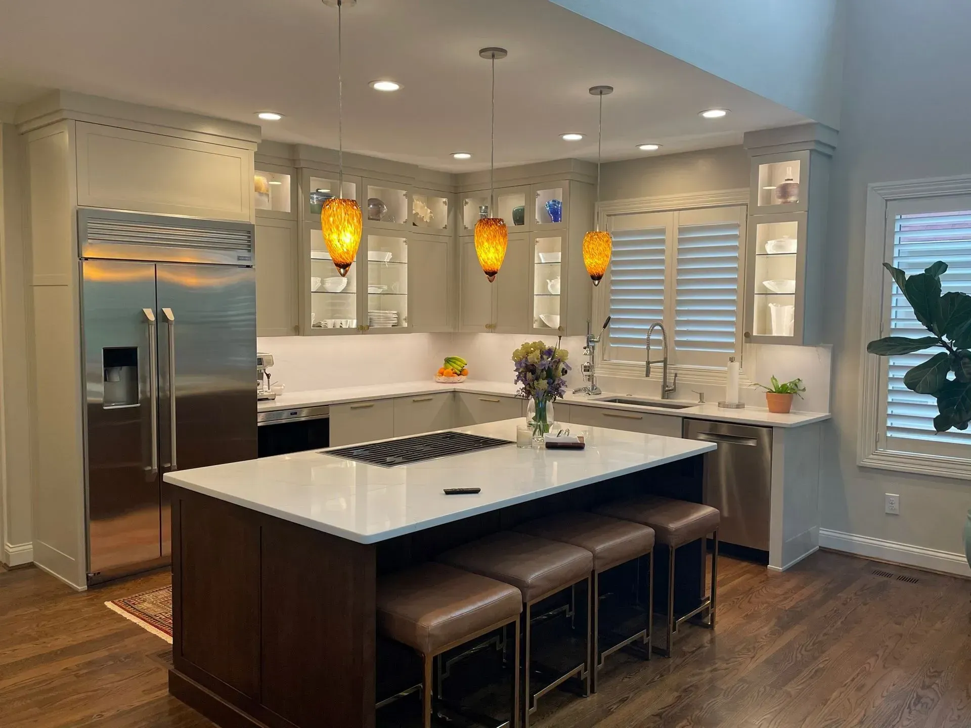Modern kitchen with a white countertop island, stainless steel appliances, and pendant lights.