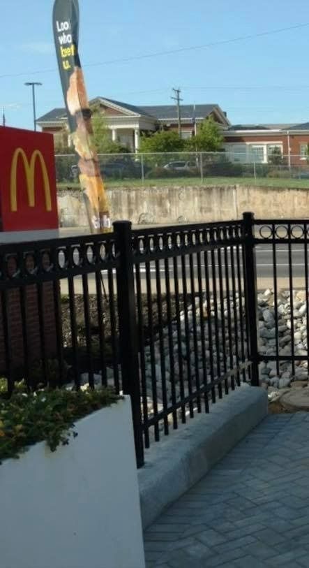McDonald’s sign beside a black fence and sidewalk near a street