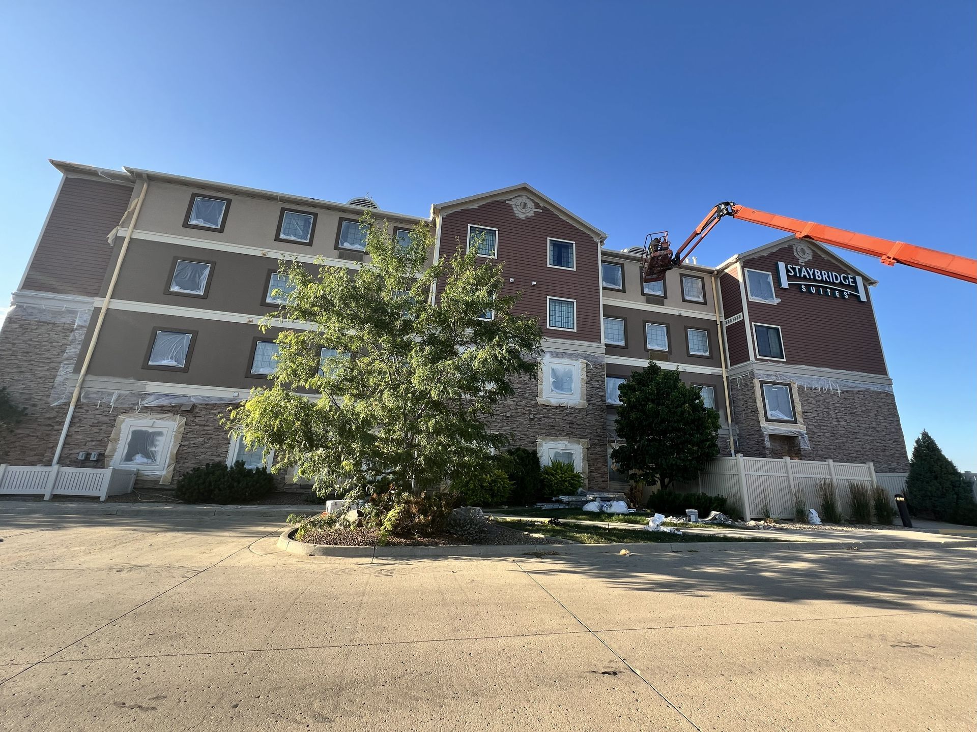 Hotel exterior with a tall crane; brown siding, stone accents, blue sky.