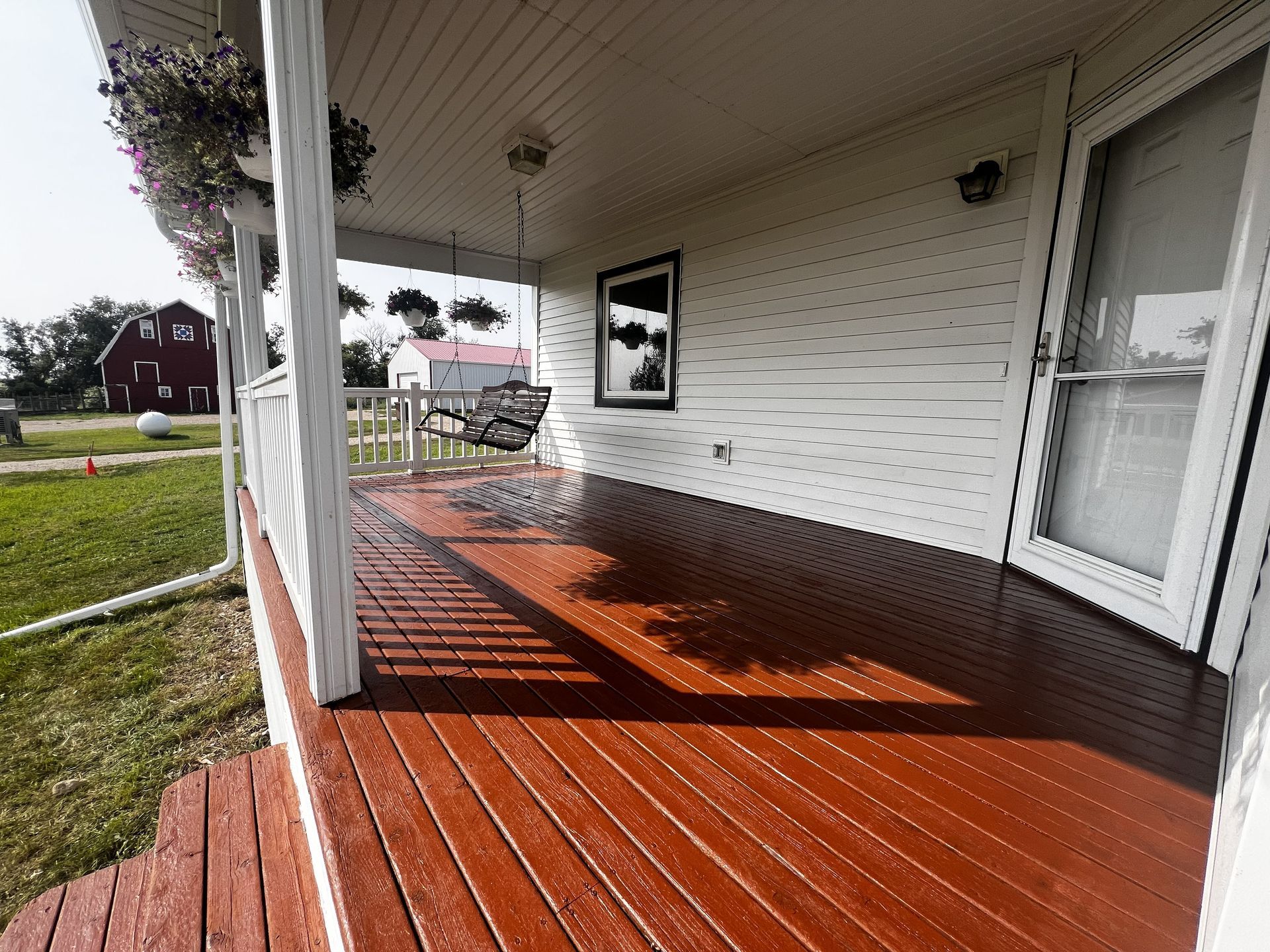 Covered porch with red-painted wooden deck; a porch swing hangs beneath the ceiling.