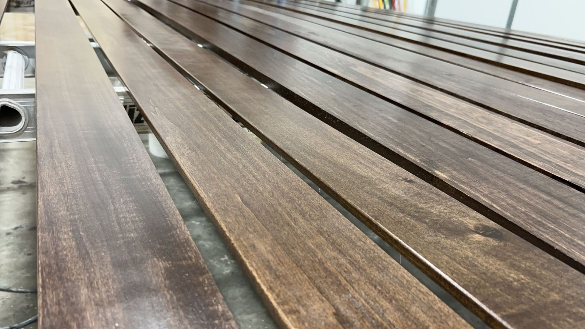 Several stained wooden planks arranged parallel. The stain color varies, ranging from light to dark brown.