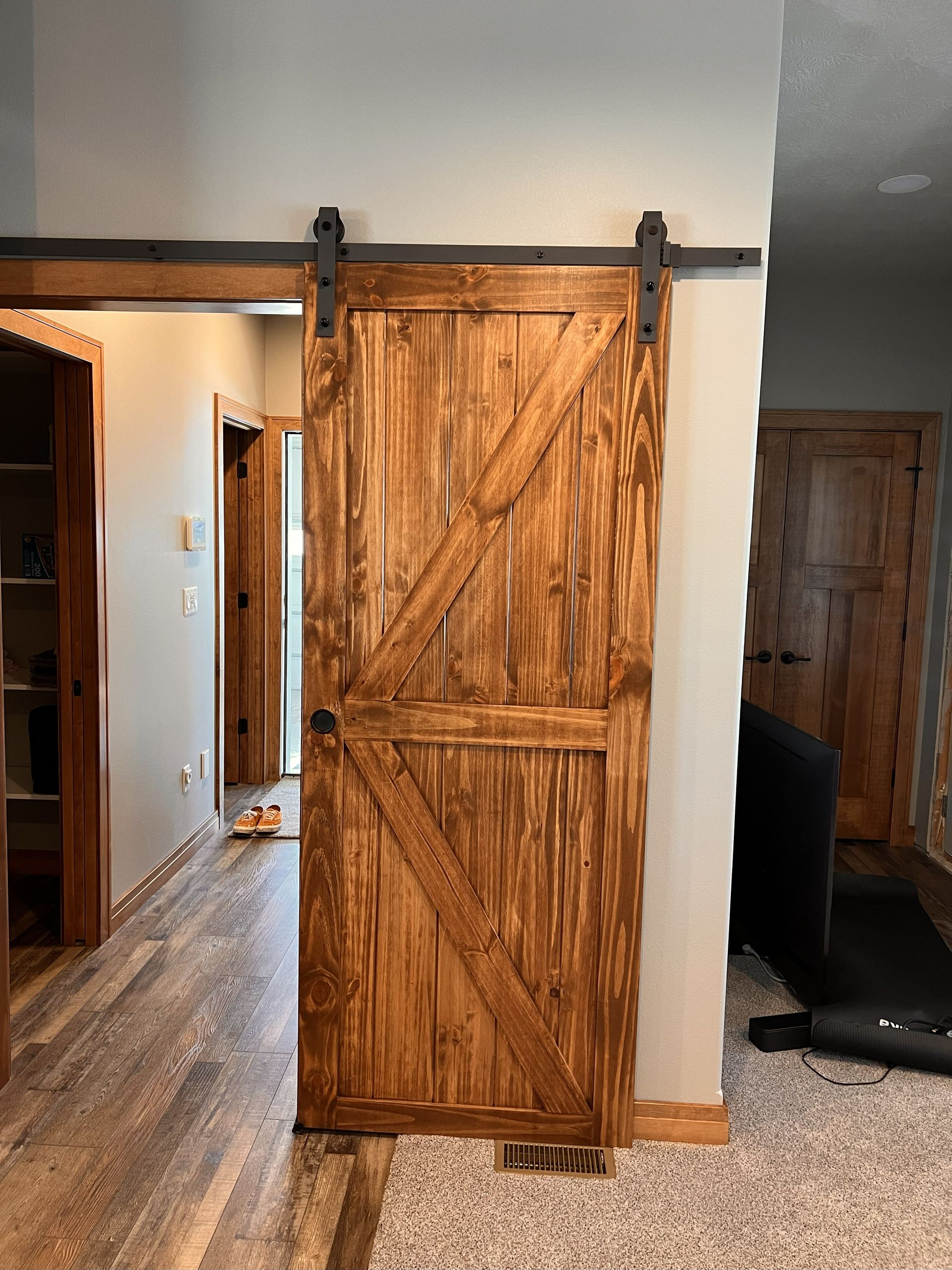 Wooden barn door on a sliding track, open doorway, hallway with wooden floors.