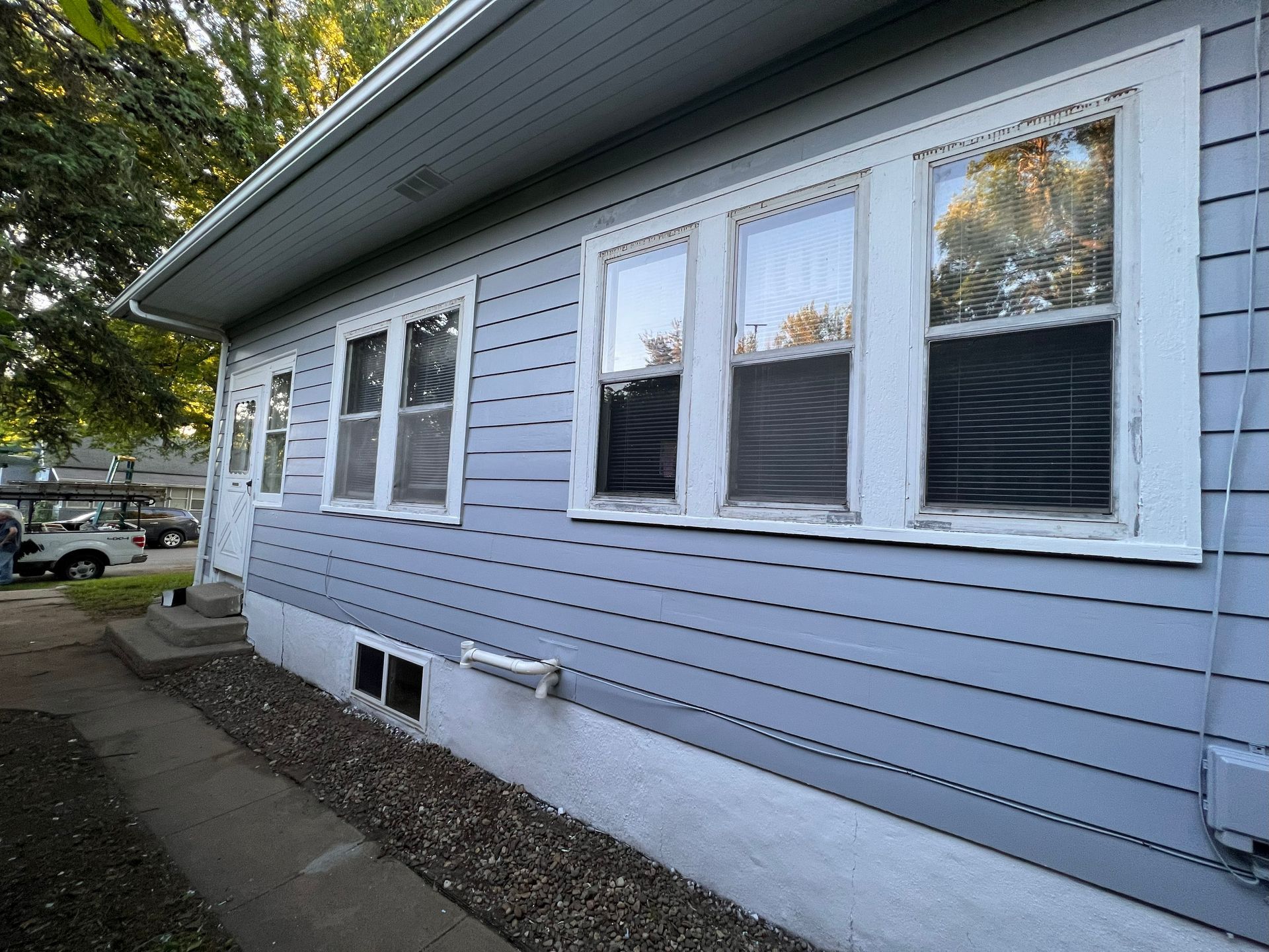 Light blue house with white trim, multiple windows, and a paved walkway.