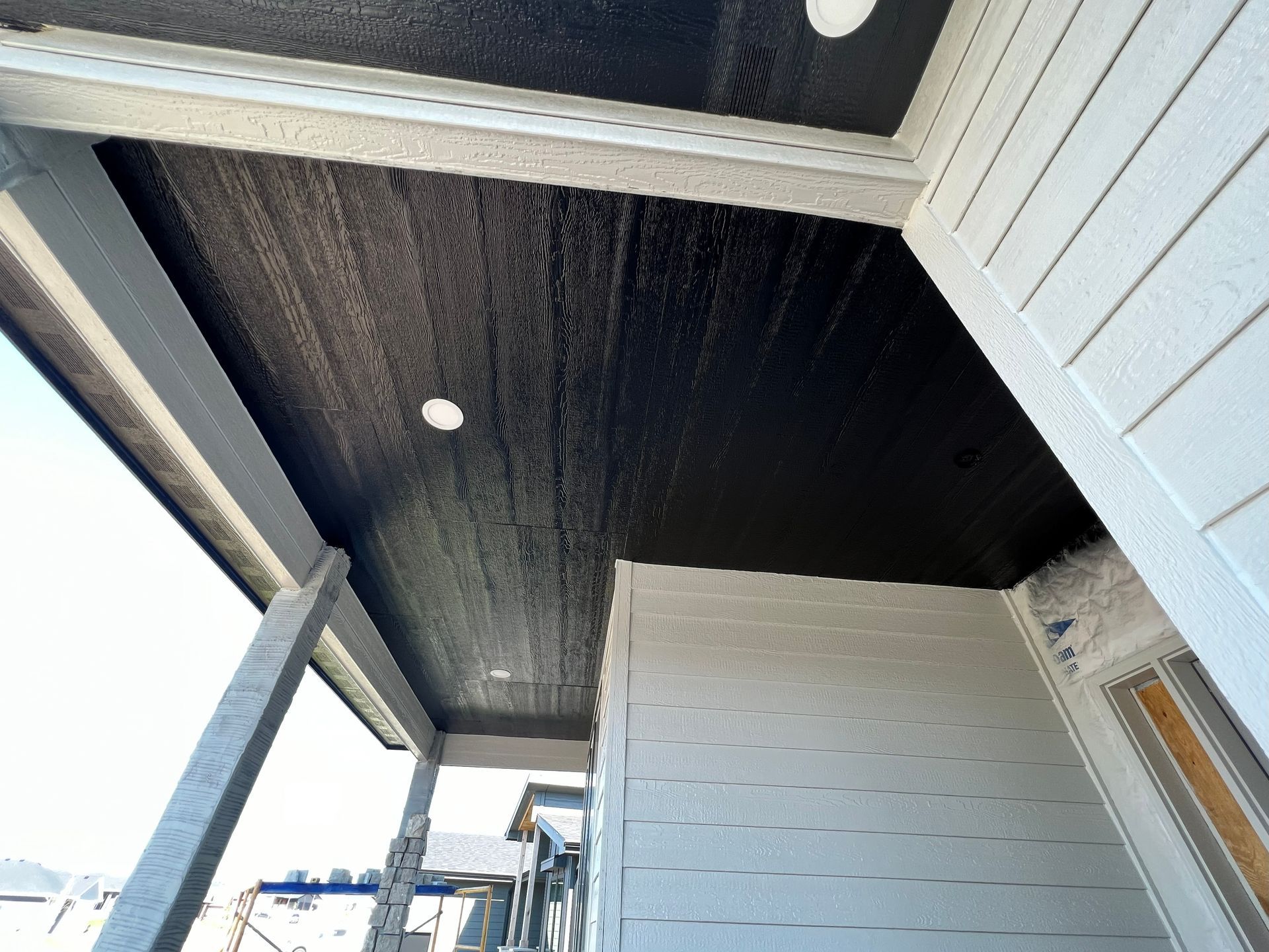 Black painted porch ceiling with white trim and recessed lighting.