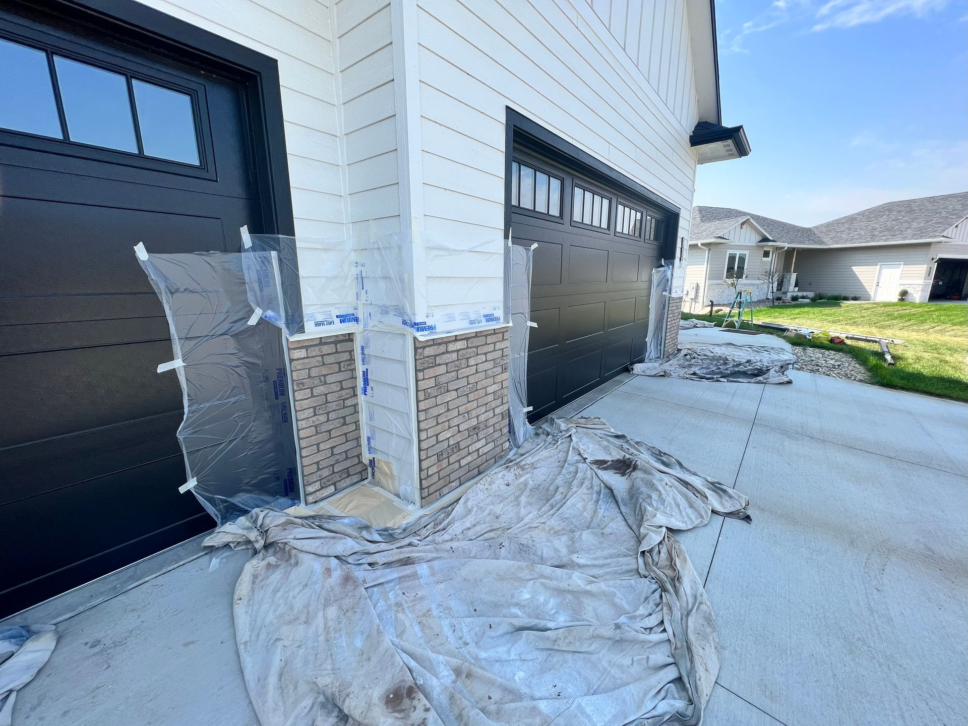 Garage with stone veneer installation in progress. Exterior view with tarps and materials visible.