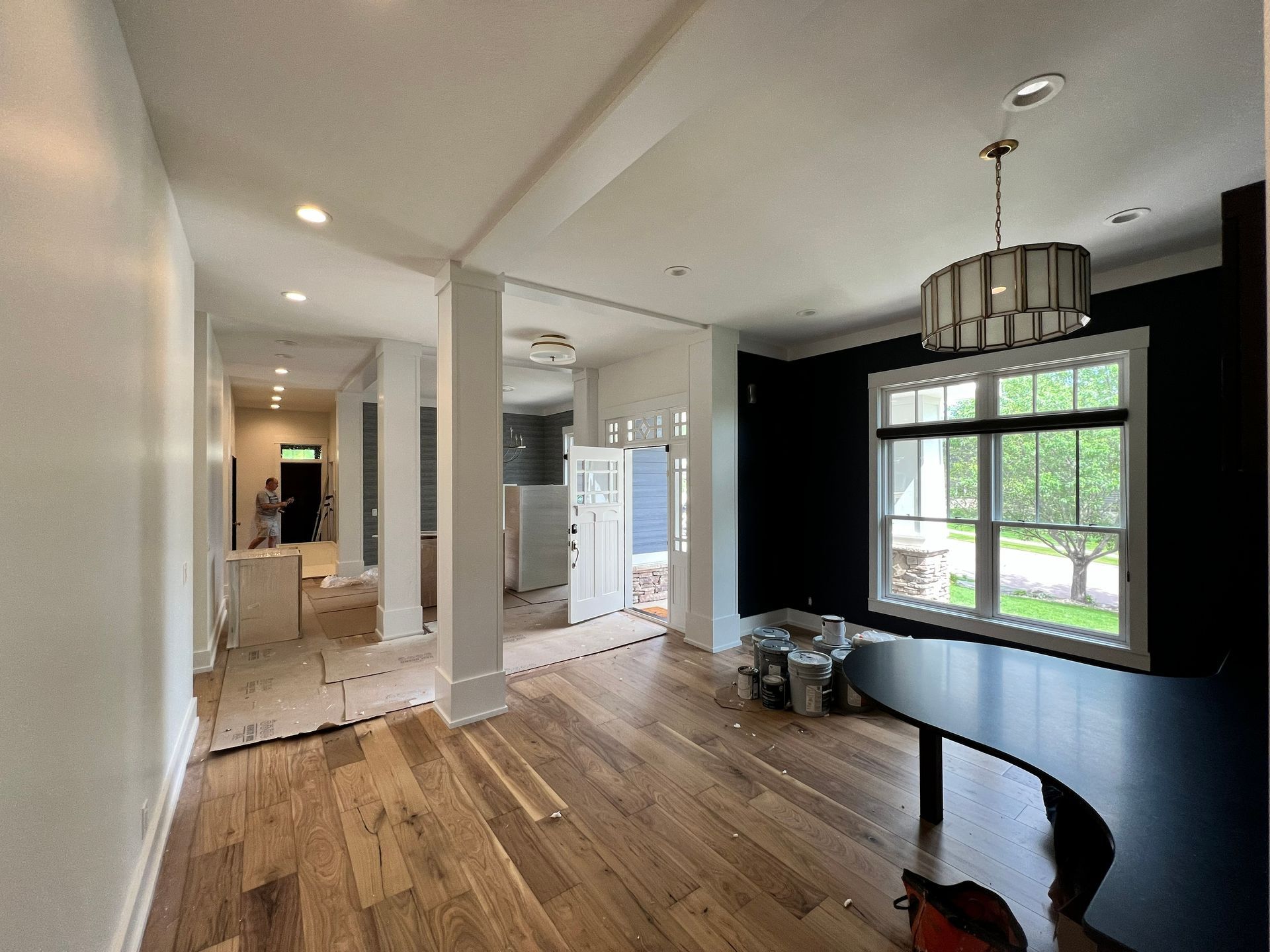 Interior with hardwood floors, white columns, black accent wall, and a large window.