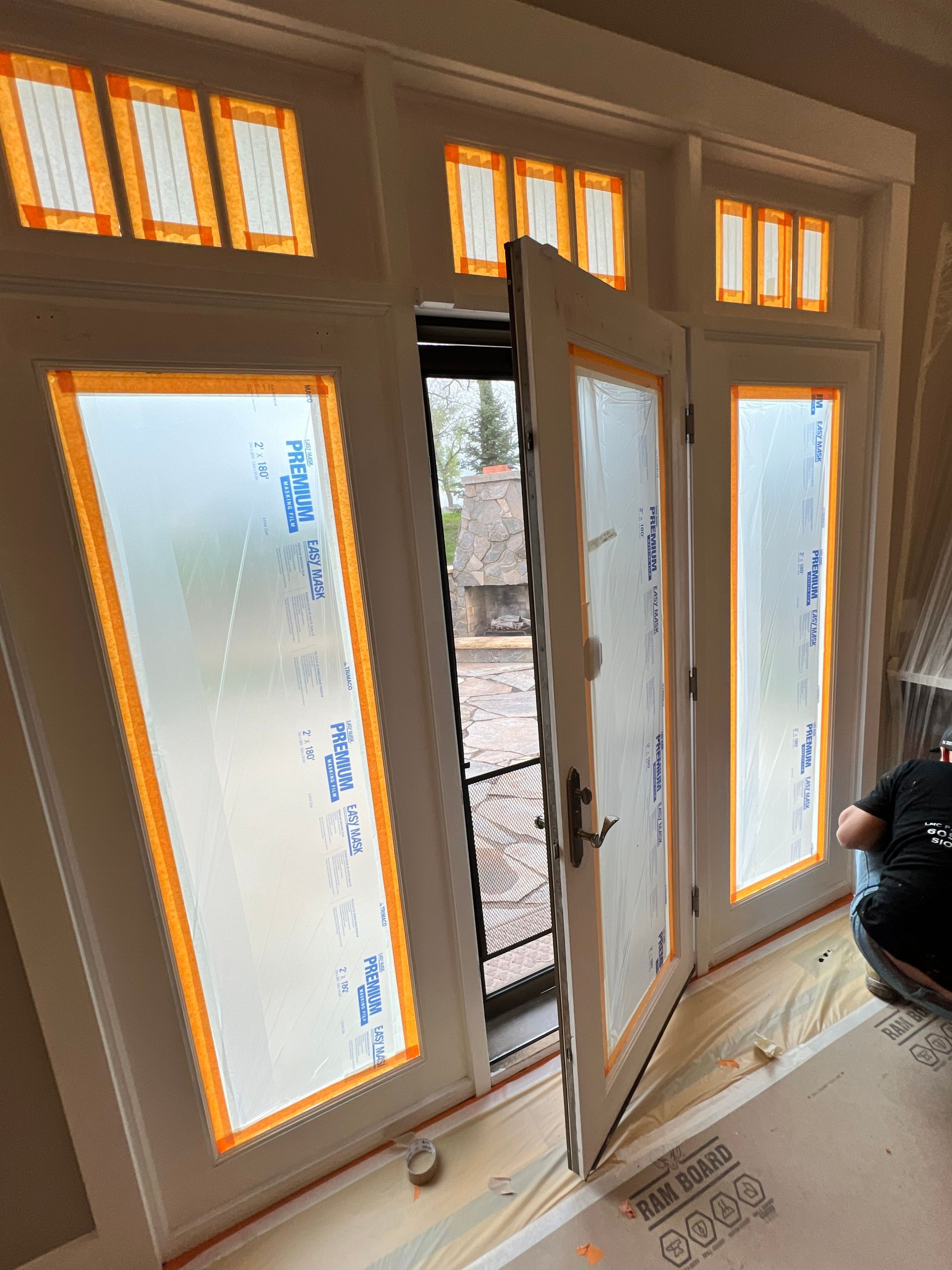 White French doors with frosted glass, one ajar, leading to an outdoor area. Orange tape lines door frames.