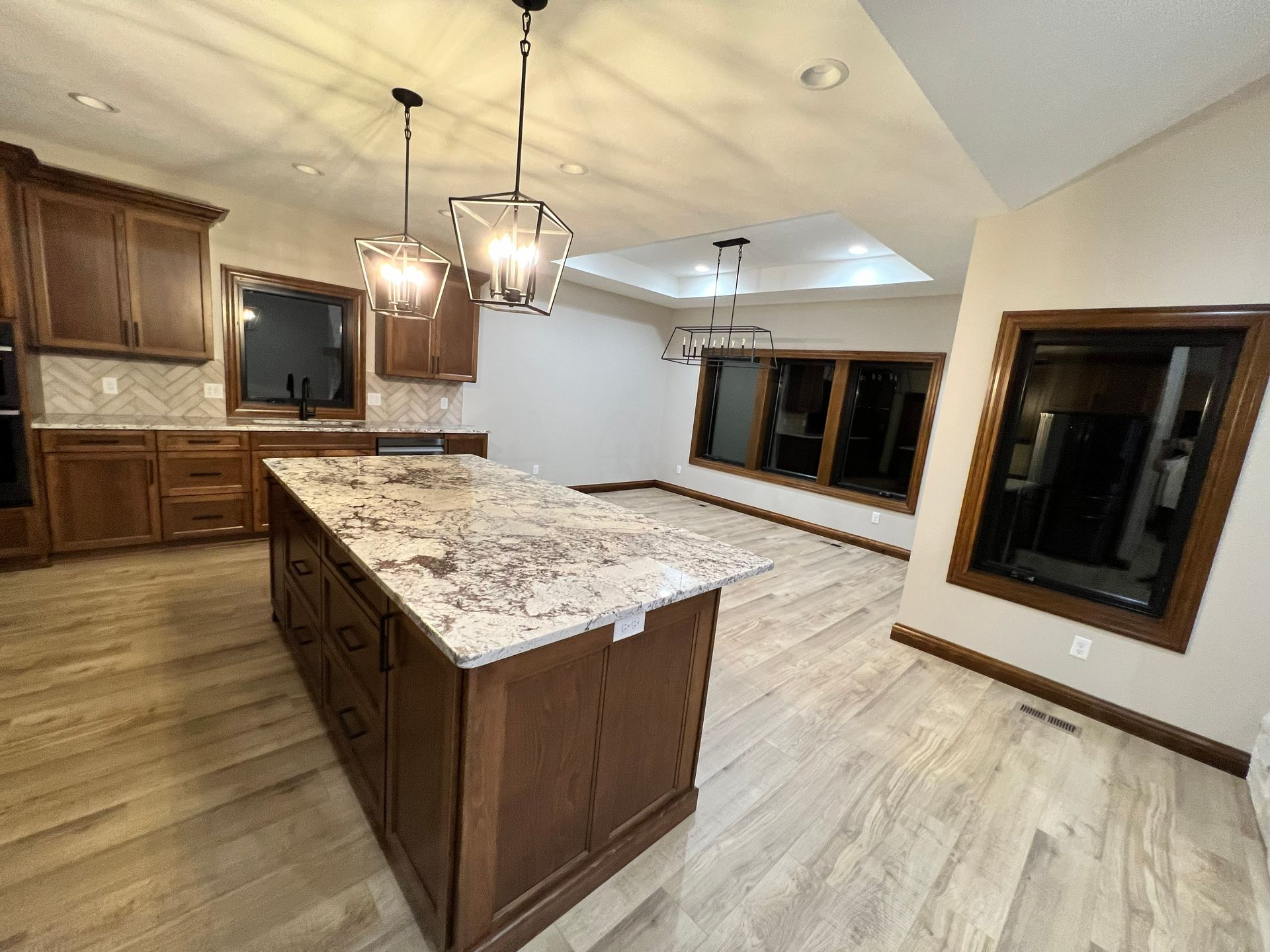 Kitchen with brown cabinets, granite island, and light wood floors.