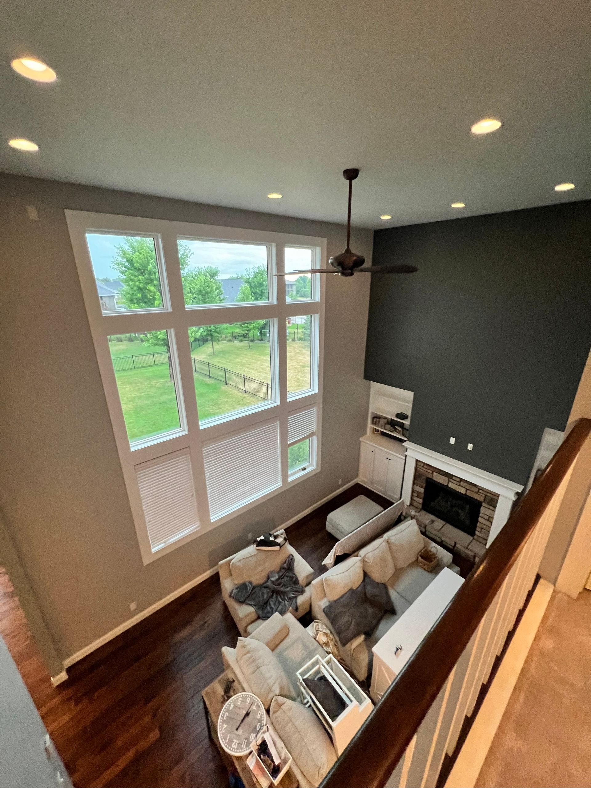 High-angle view of a living room with tall windows, a fireplace, and a dark accent wall.