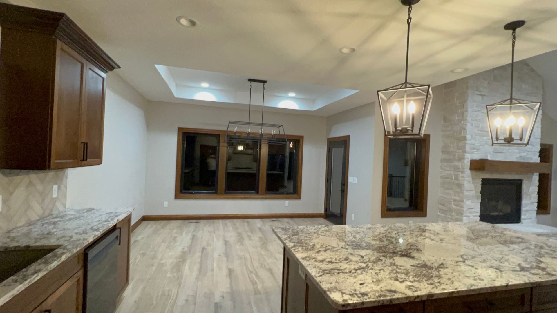 Kitchen with dark cabinets, granite counters, wooden floors, and a stone fireplace.