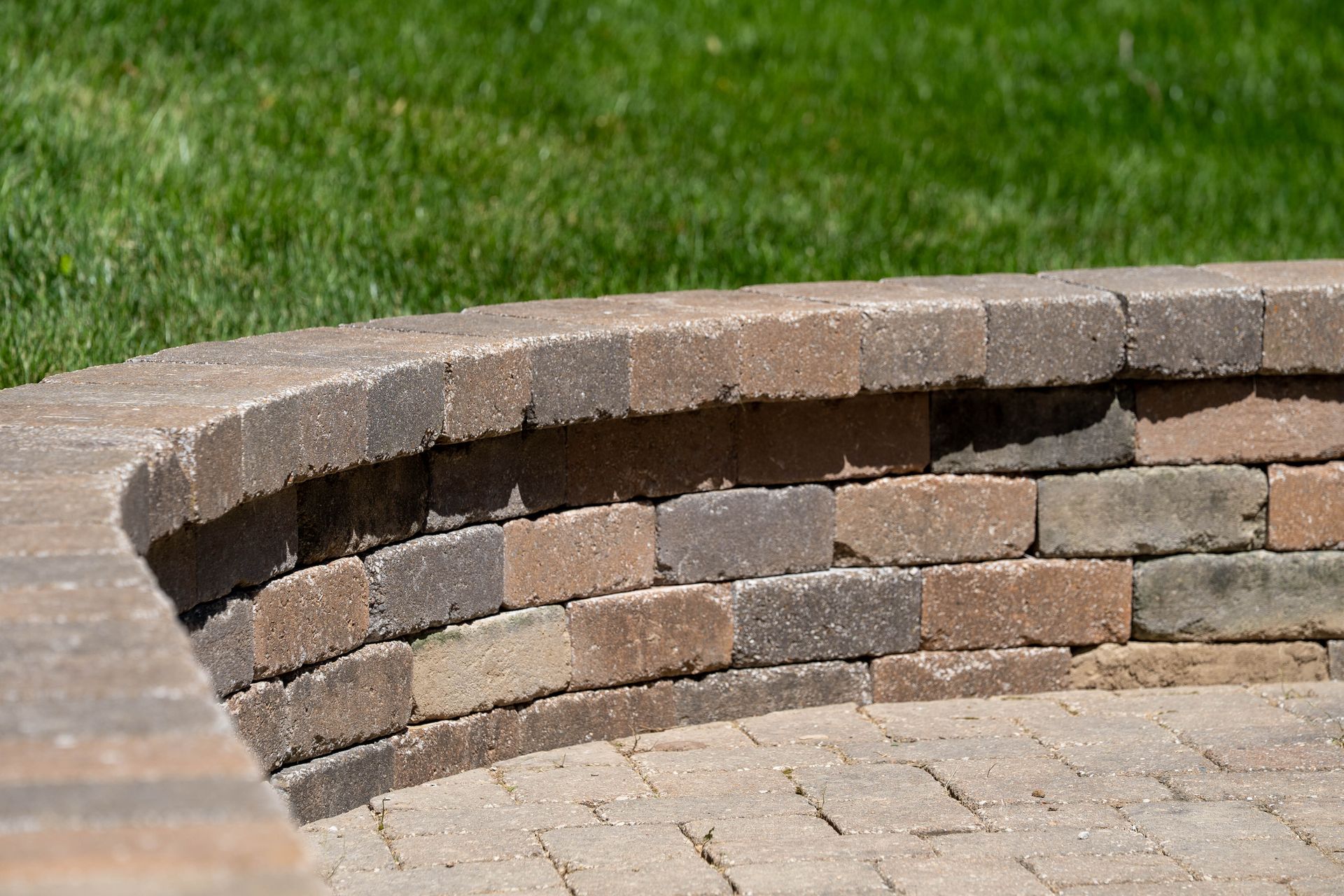 Curved brick retaining wall with green grass in background.