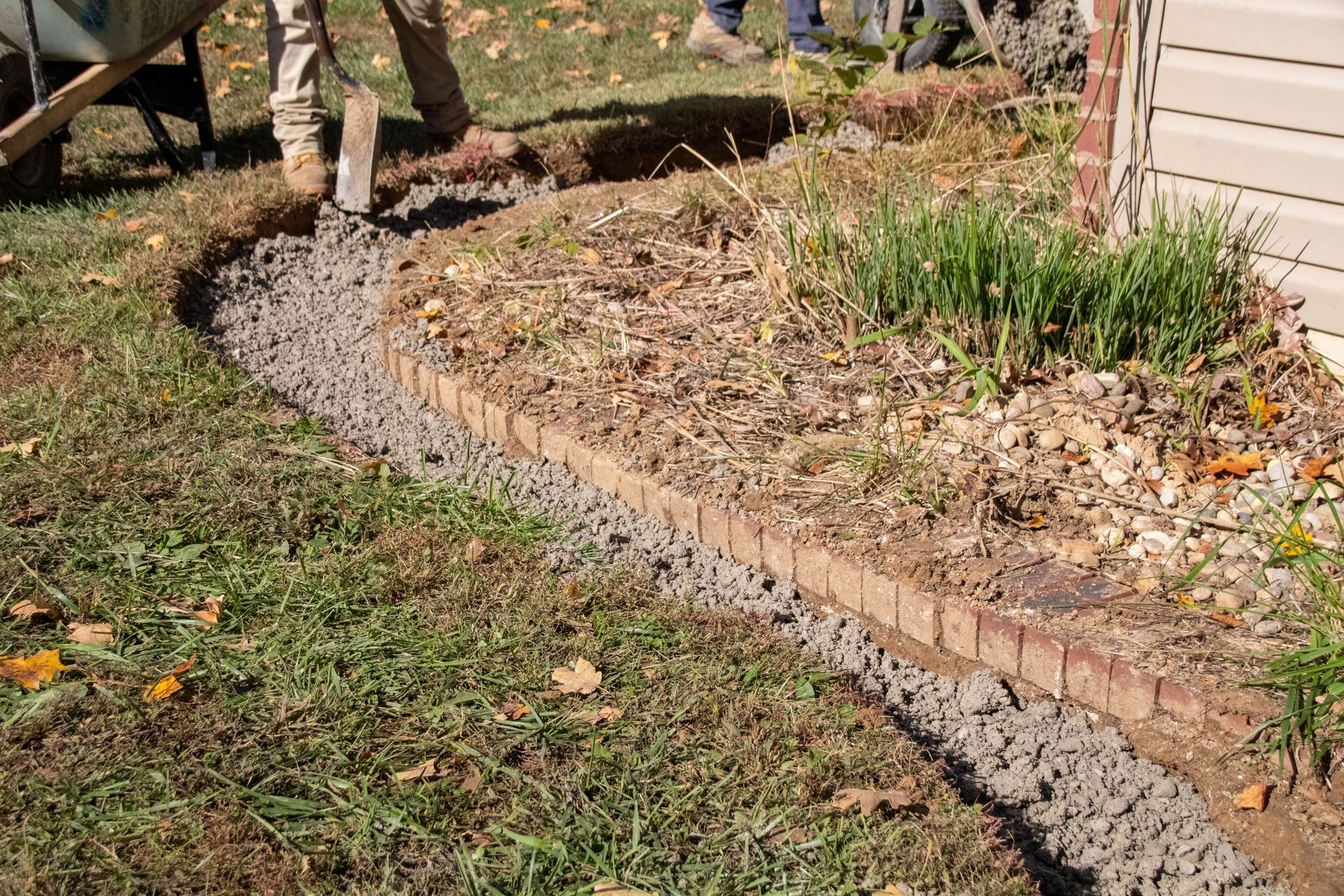 Flower bed border being installed with bricks and gravel; person in background.