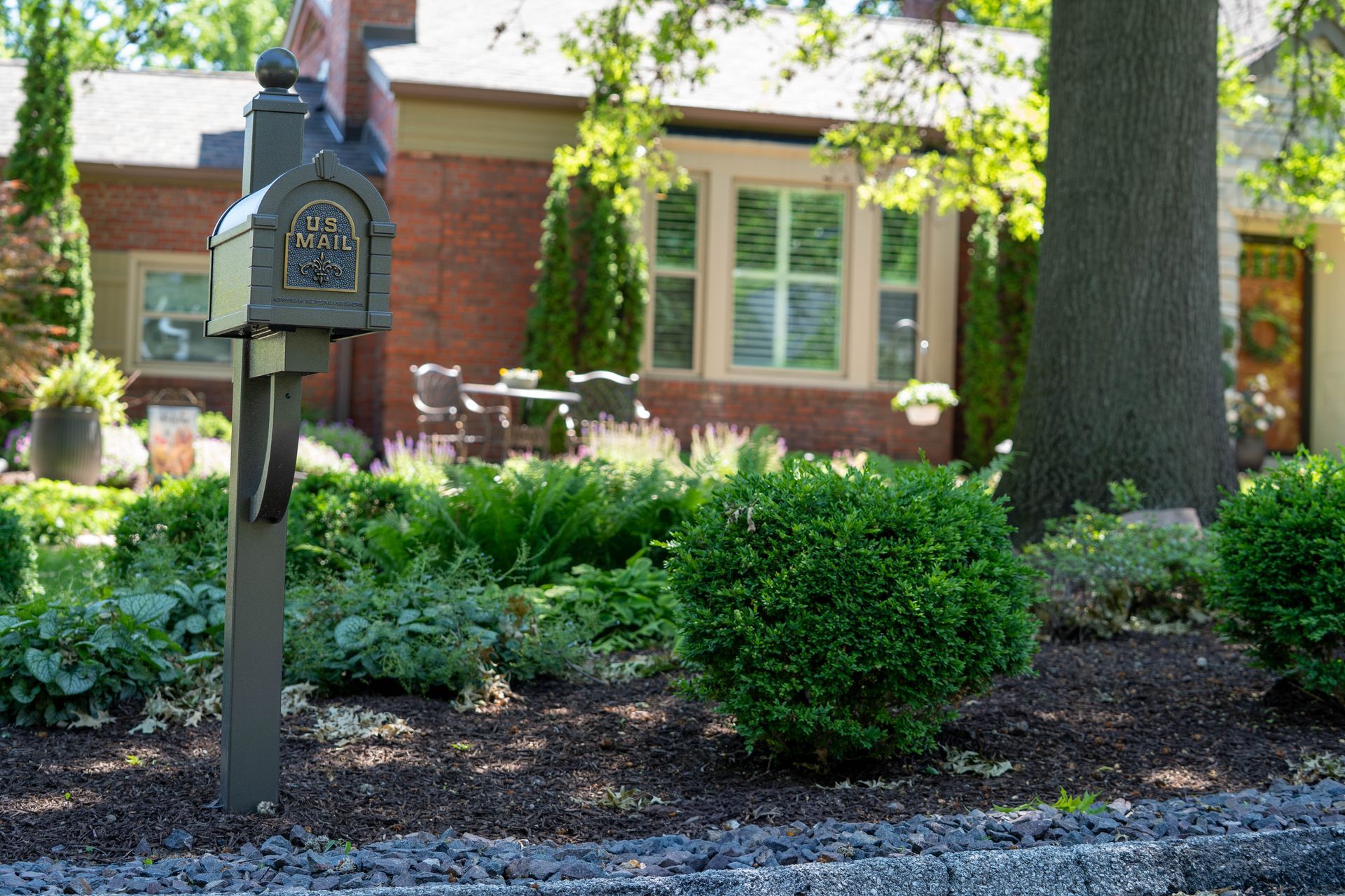 Mailbox in front of a brick house with a well-kept garden.