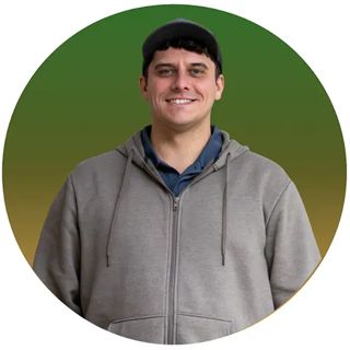 Man in gray hoodie and baseball cap smiling, set against a green and yellow gradient circle.