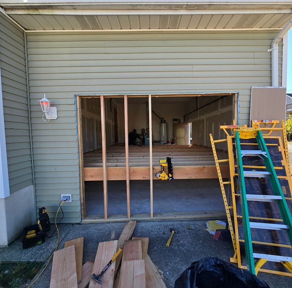A garage that is being remodeled with a ladder in front of it