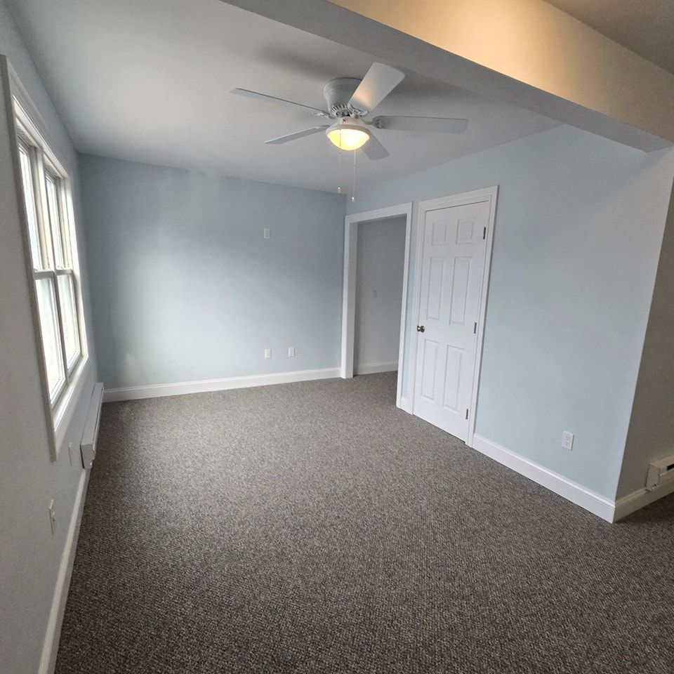 An empty room with a ceiling fan and a window