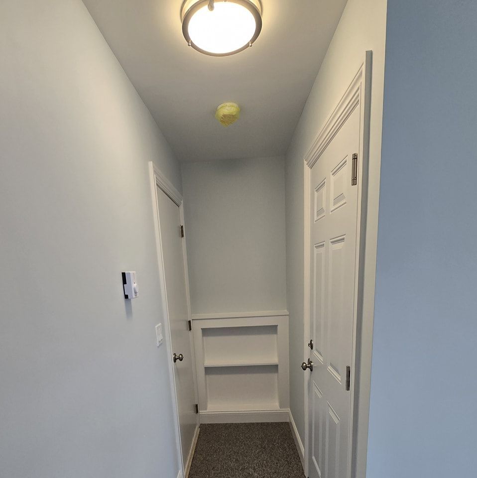 A hallway with white doors and a light on the ceiling