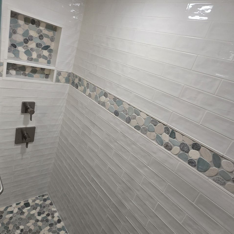 A shower with white tiles and a stone border.