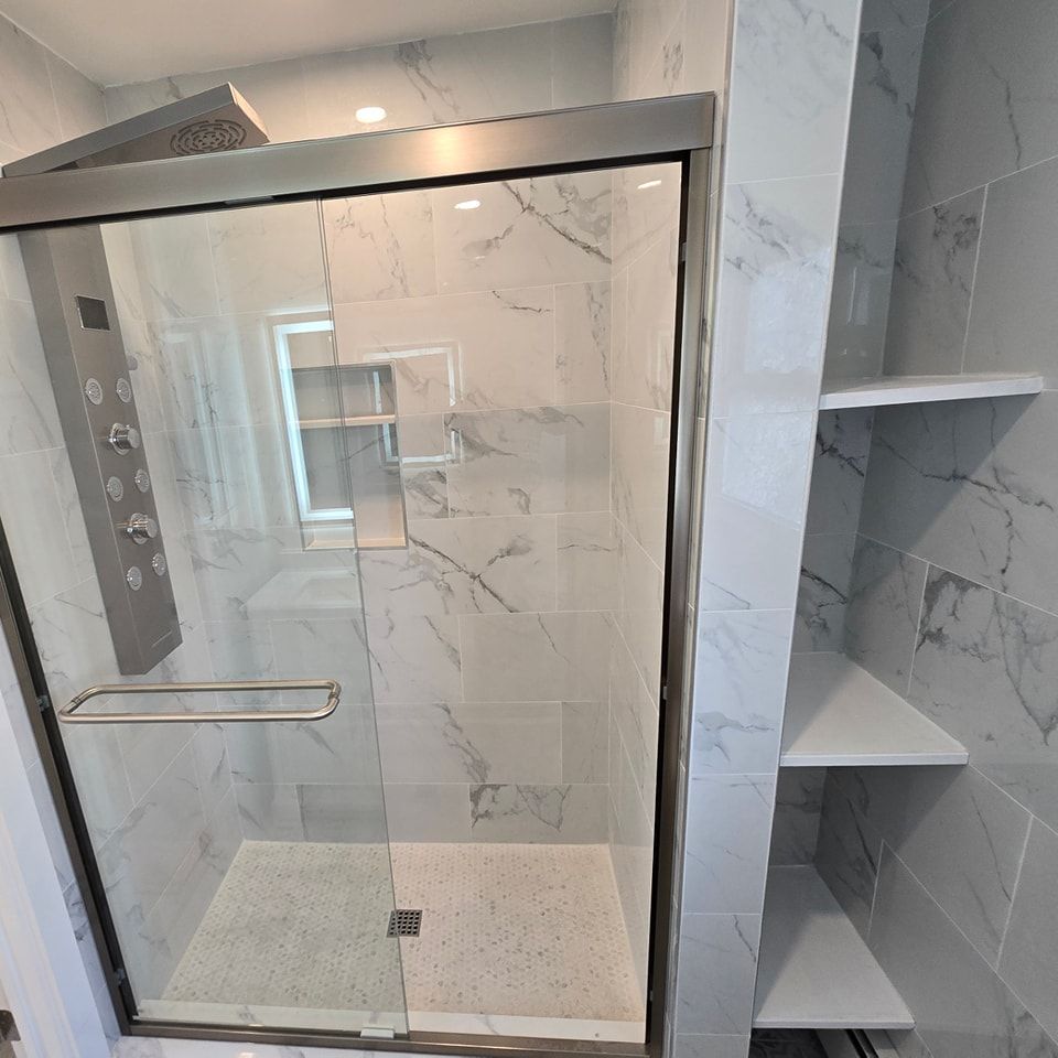 A bathroom with marble tiles and a glass shower door