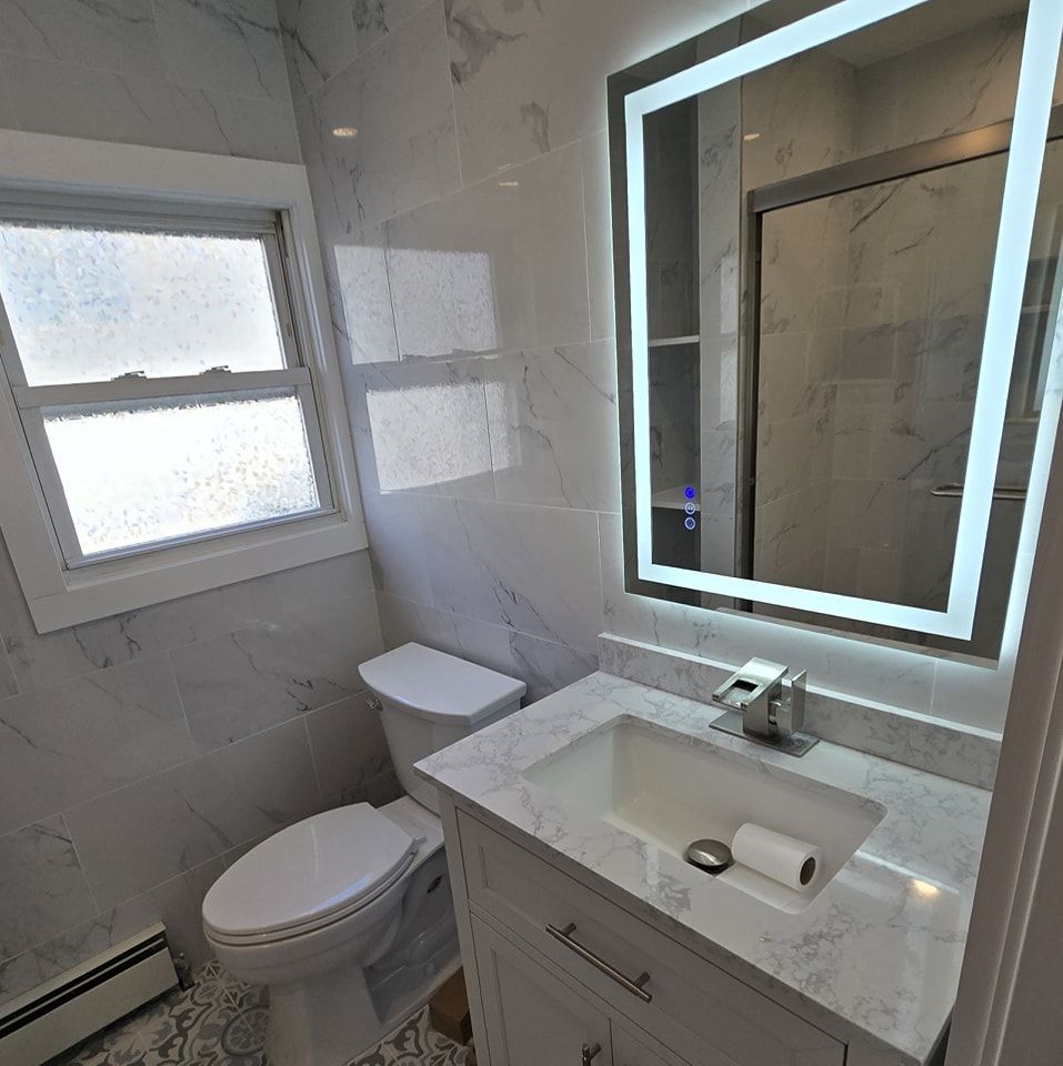 A bathroom with a toilet , sink and mirror