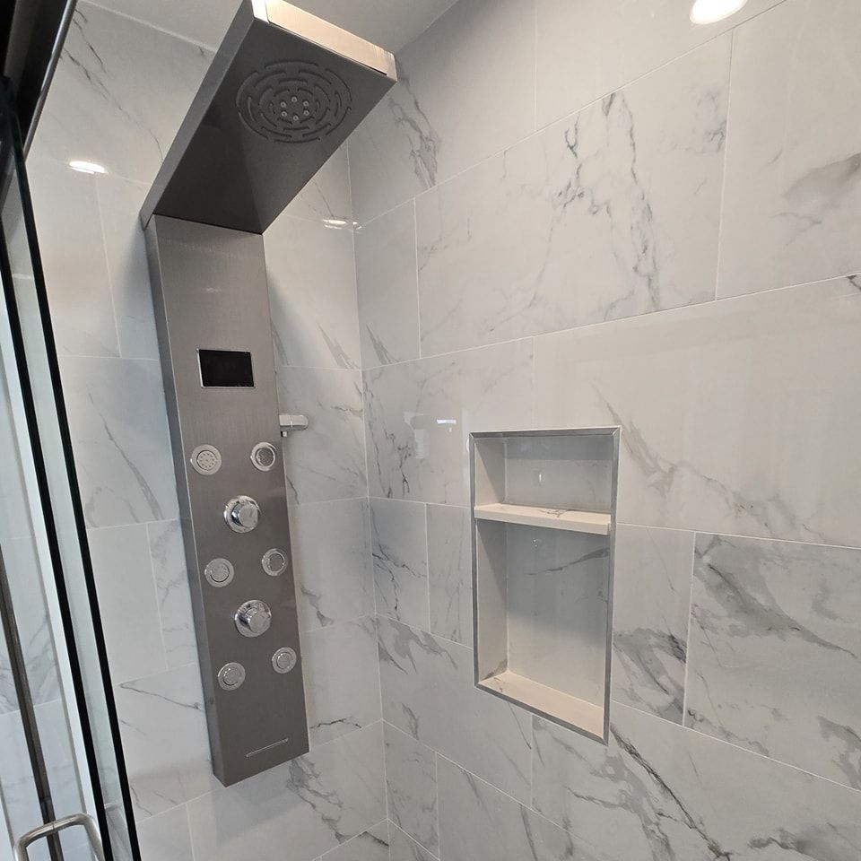 A bathroom with marble tiles and a shower head.