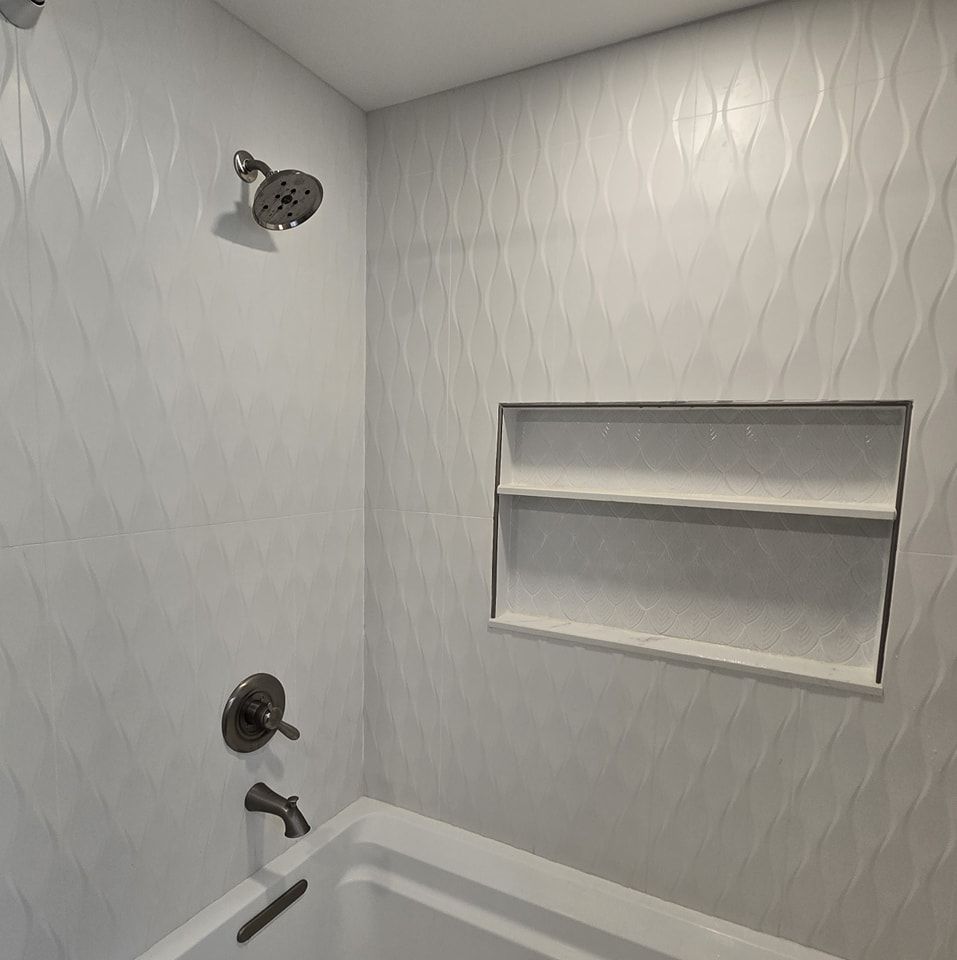 A bathroom with a bathtub , shower , and shelf.