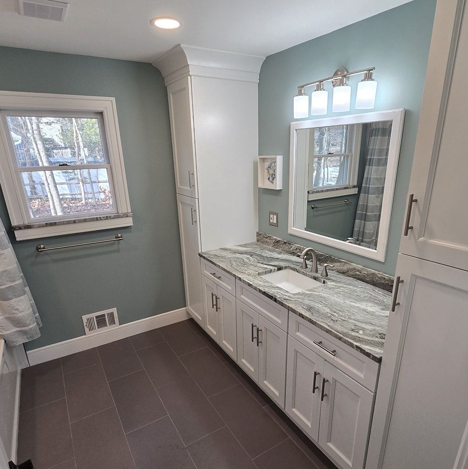 A bathroom with a sink , mirror and window