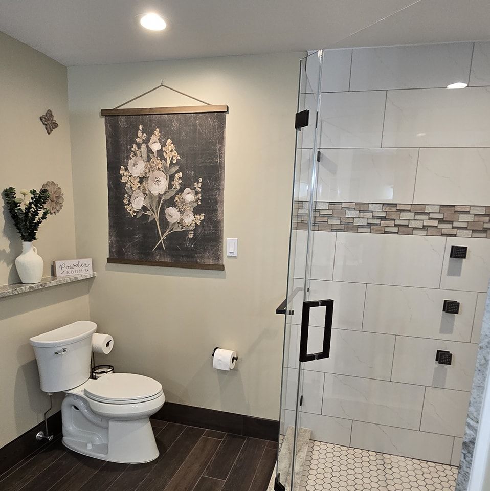 A bathroom with a toilet a shower and a painting on the wall