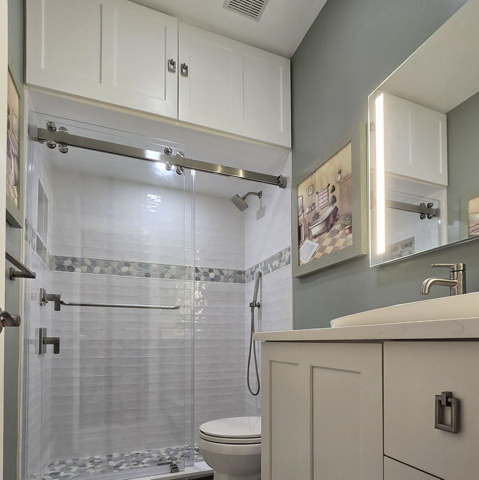A bathroom with a toilet a sink and a sliding glass shower door