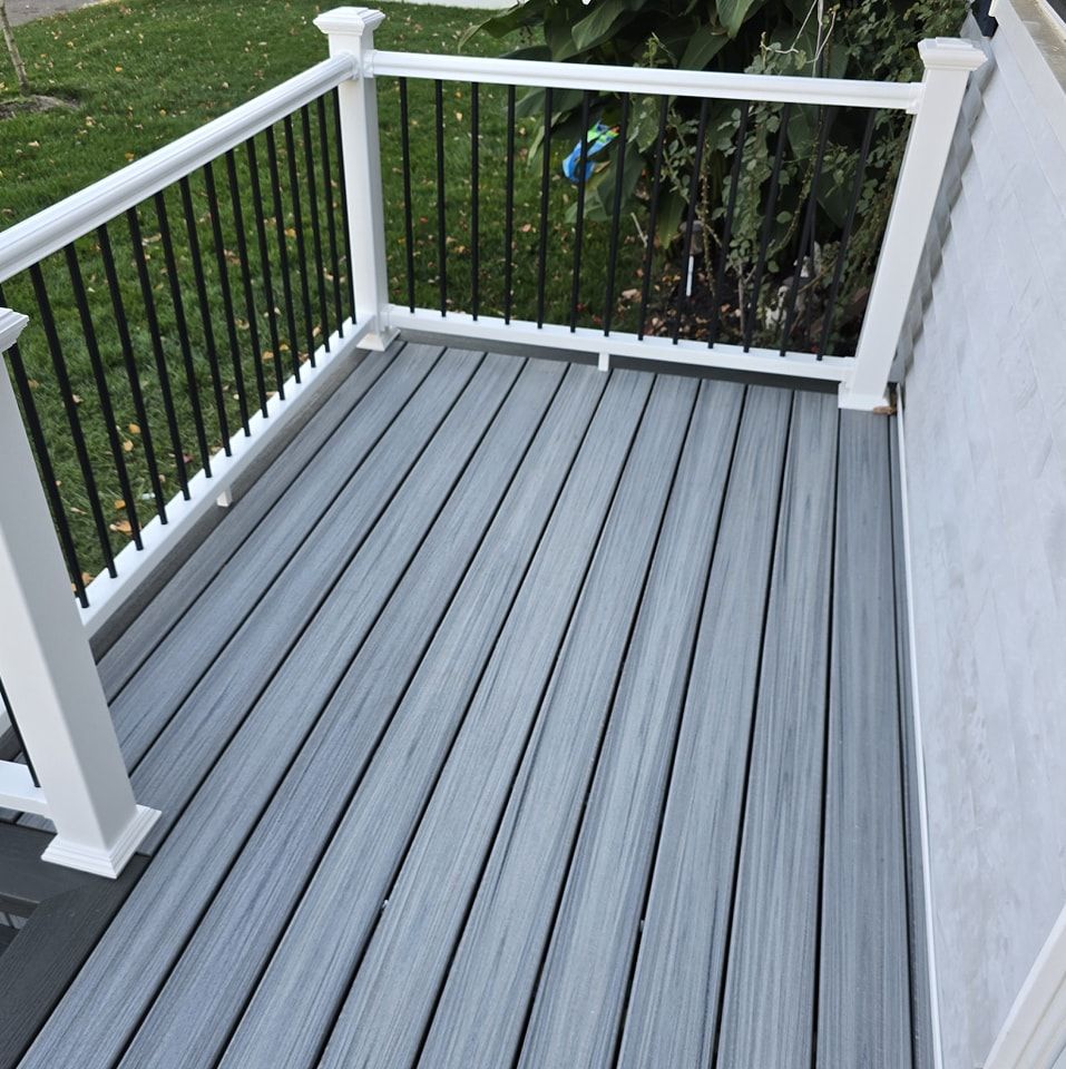 A gray deck with a white railing and a black railing