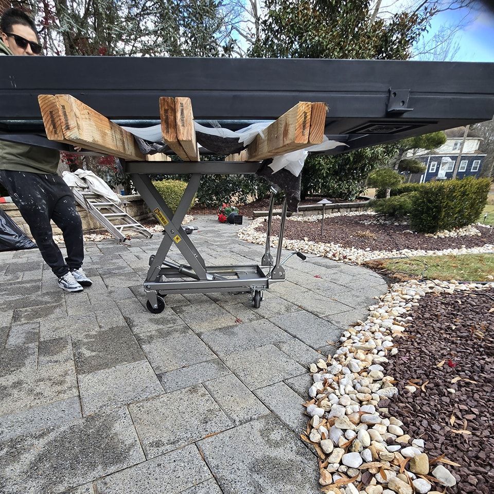 A man is carrying a large piece of wood on a cart.
