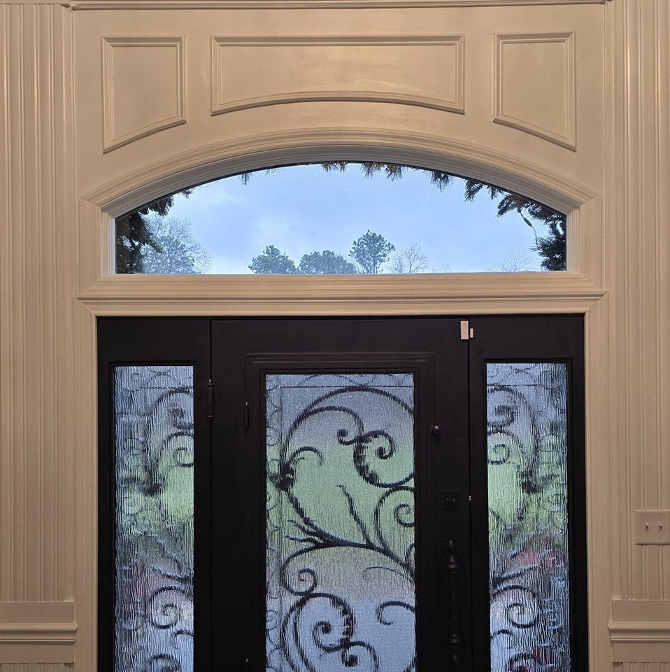 A black door with a wrought iron design and a window above it.