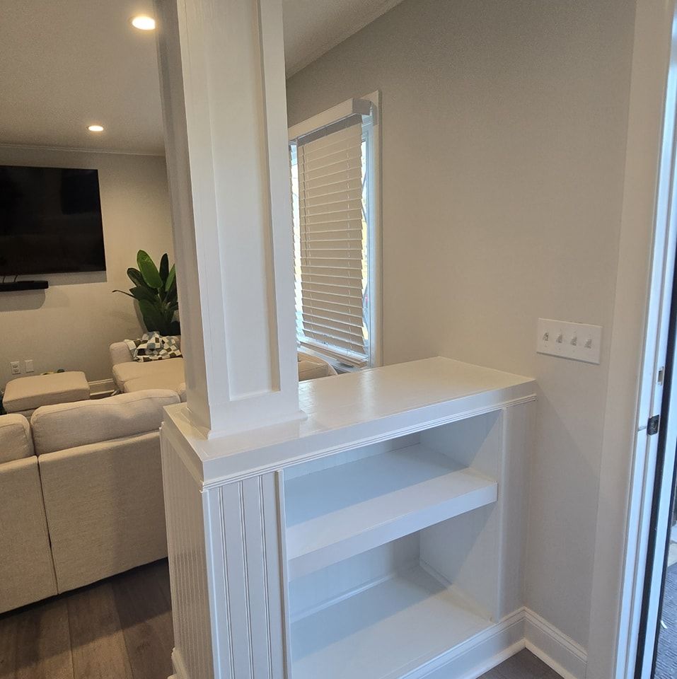 A white shelf in a living room next to a window.