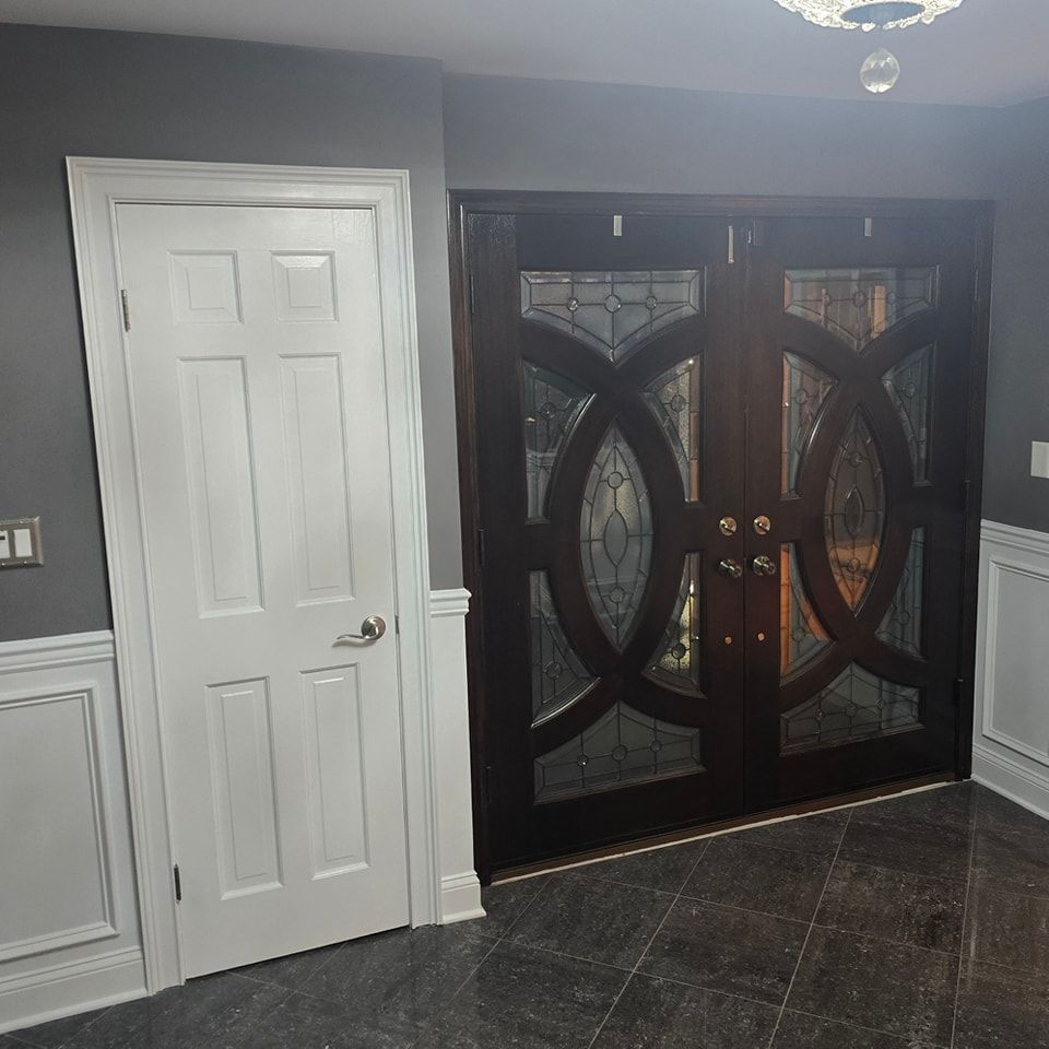A room with two doors and a chandelier hanging from the ceiling