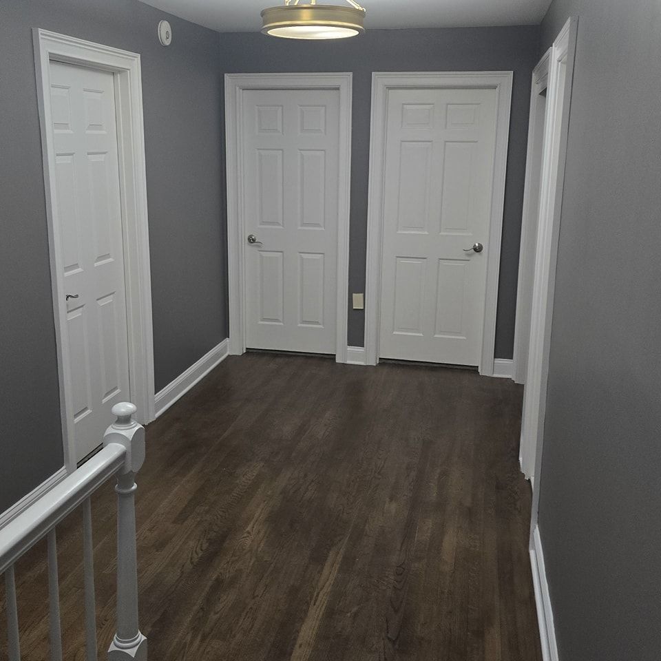 A hallway with wooden floors and white doors in a house.