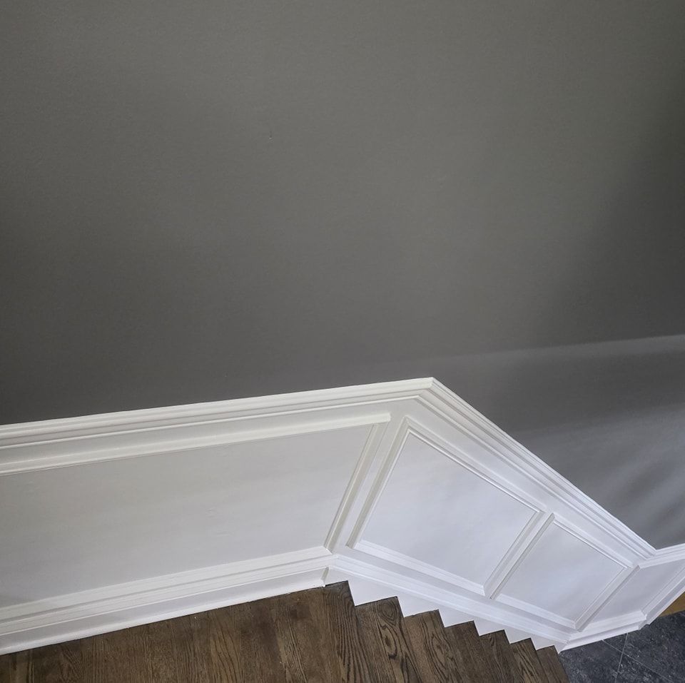 A staircase with white trim and a gray wall.
