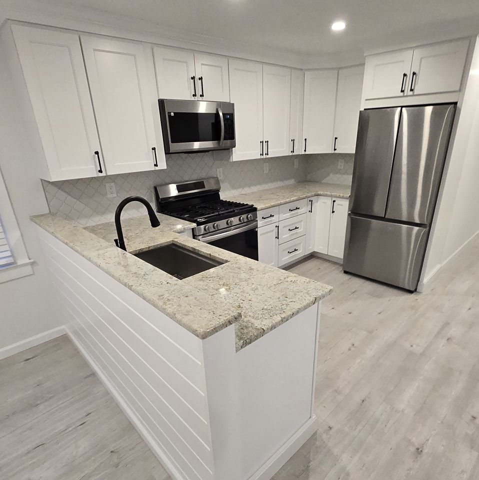A kitchen with white cabinets , stainless steel appliances , granite counter tops and a sink.