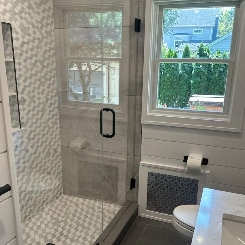 A bathroom with a glass shower door and a window