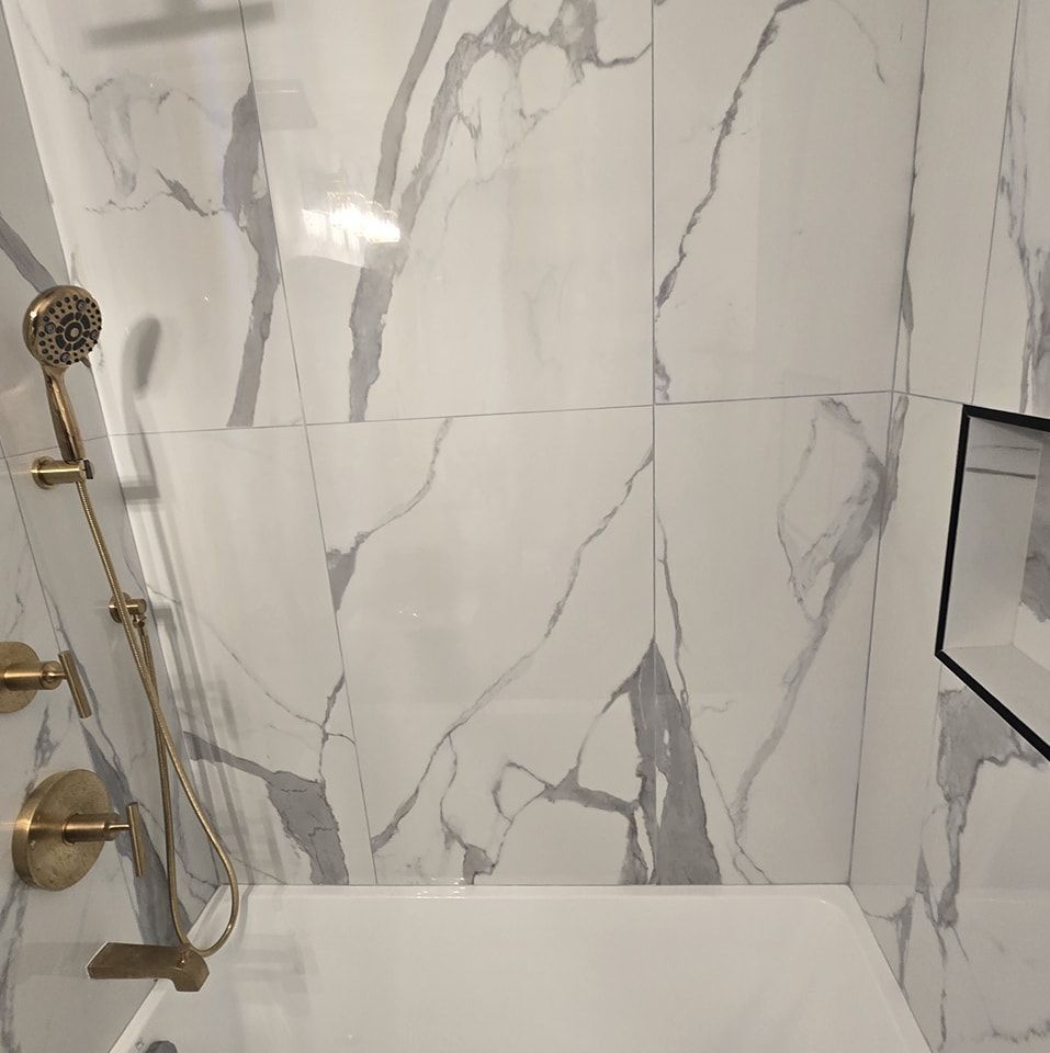 A bathroom with marble tiles and a bathtub with a shower head.