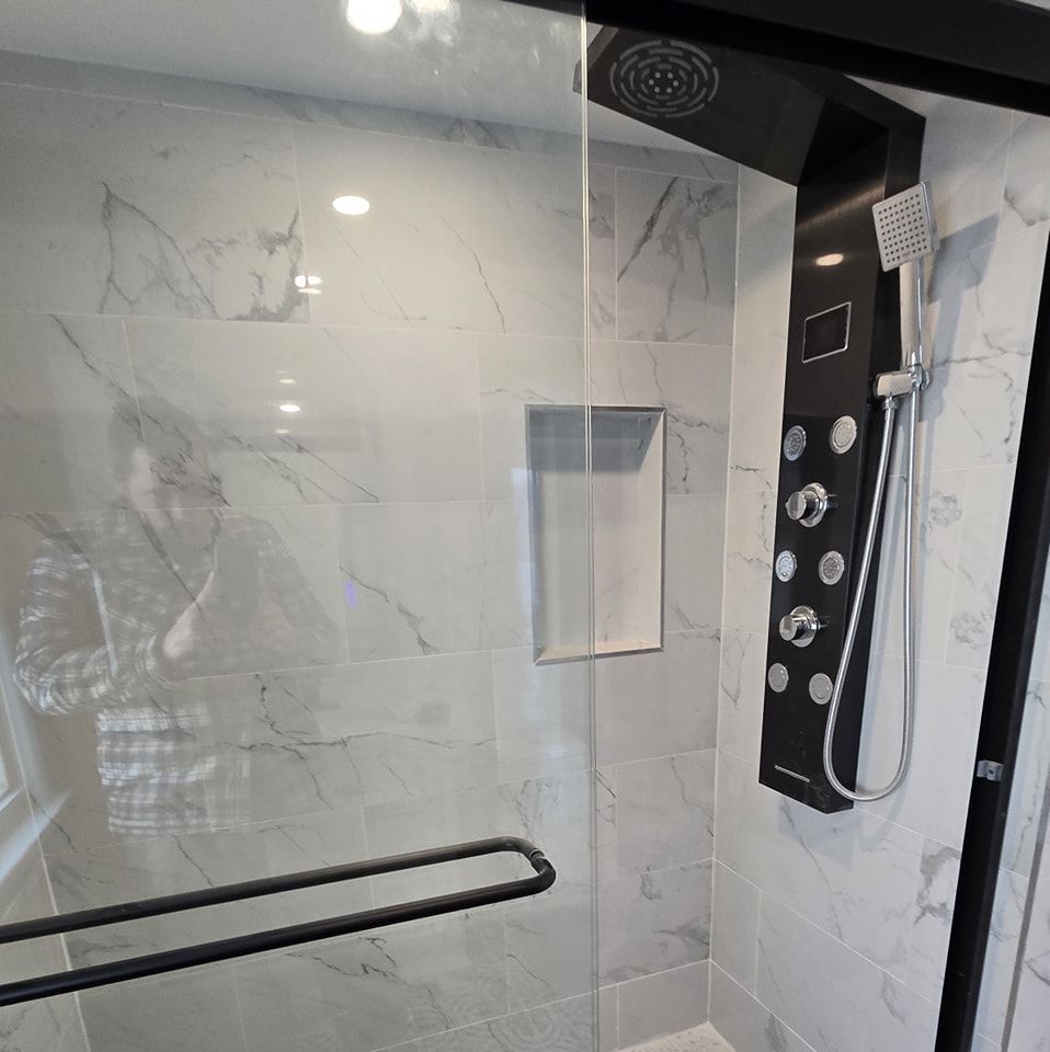 A shower with a glass door and a black shower head