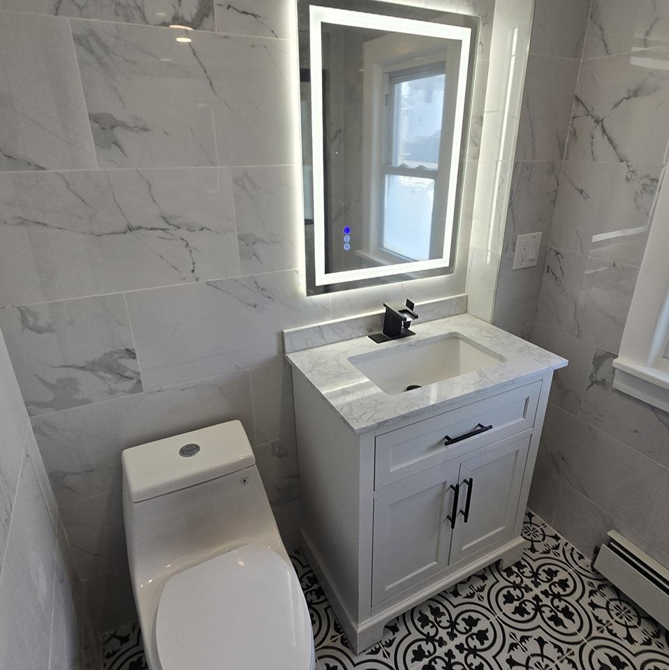 A bathroom with a toilet , sink and mirror.
