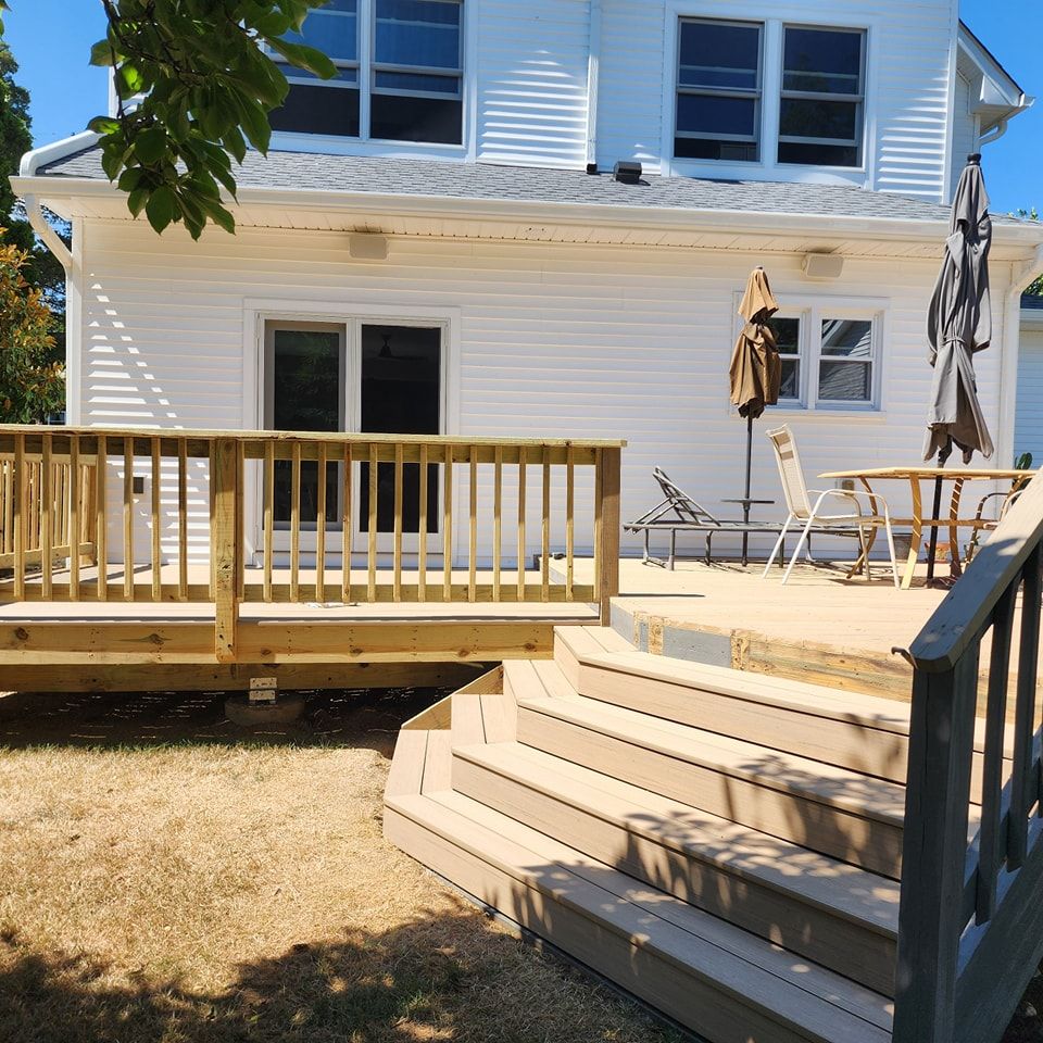 A white house with a wooden deck and stairs