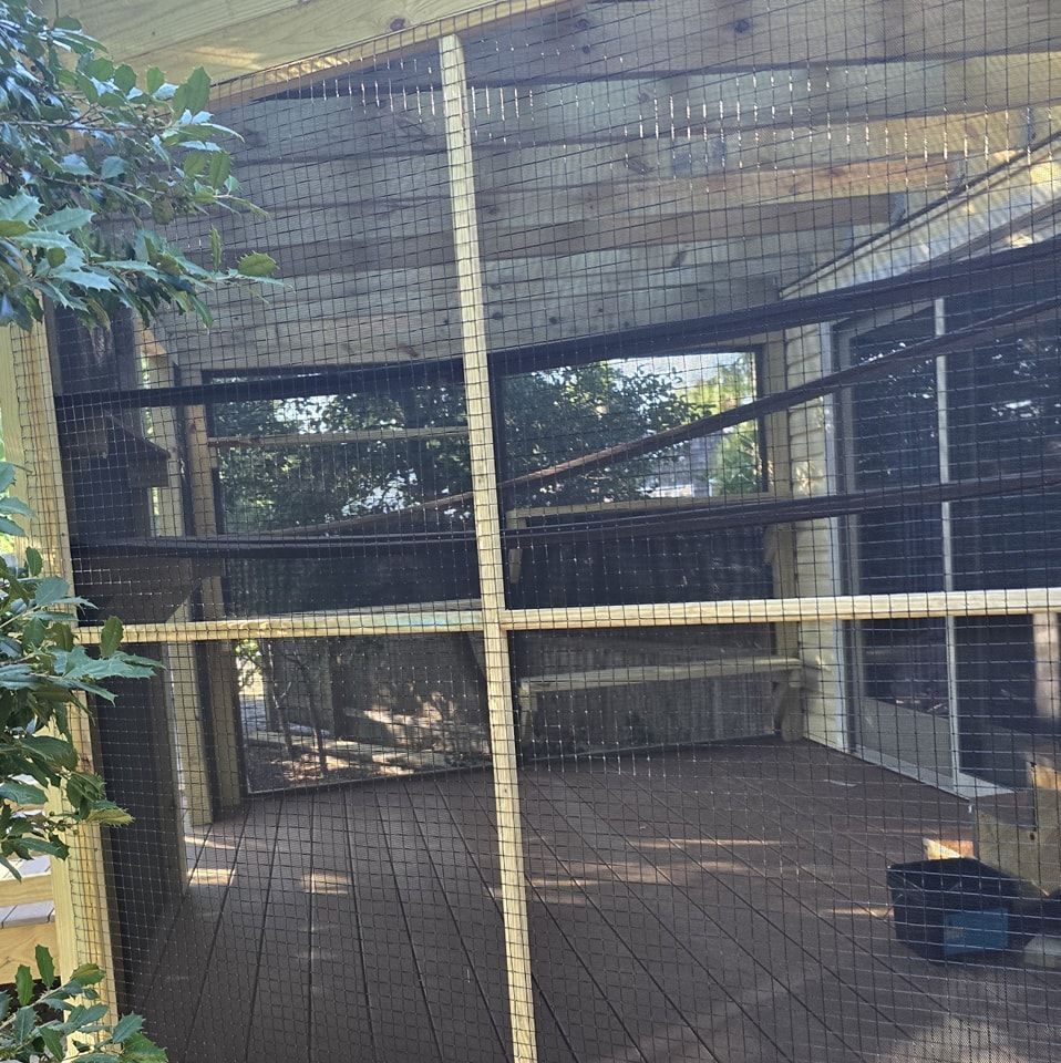 A fenced in area with a wooden floor and trees in the background