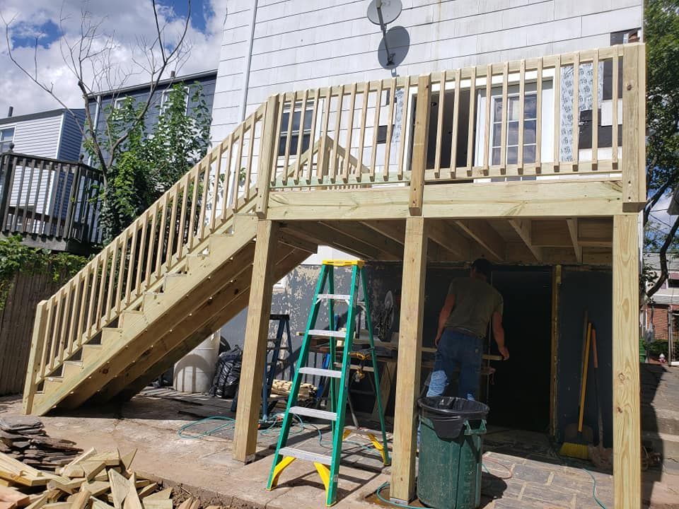 A man is working on a wooden deck with stairs.