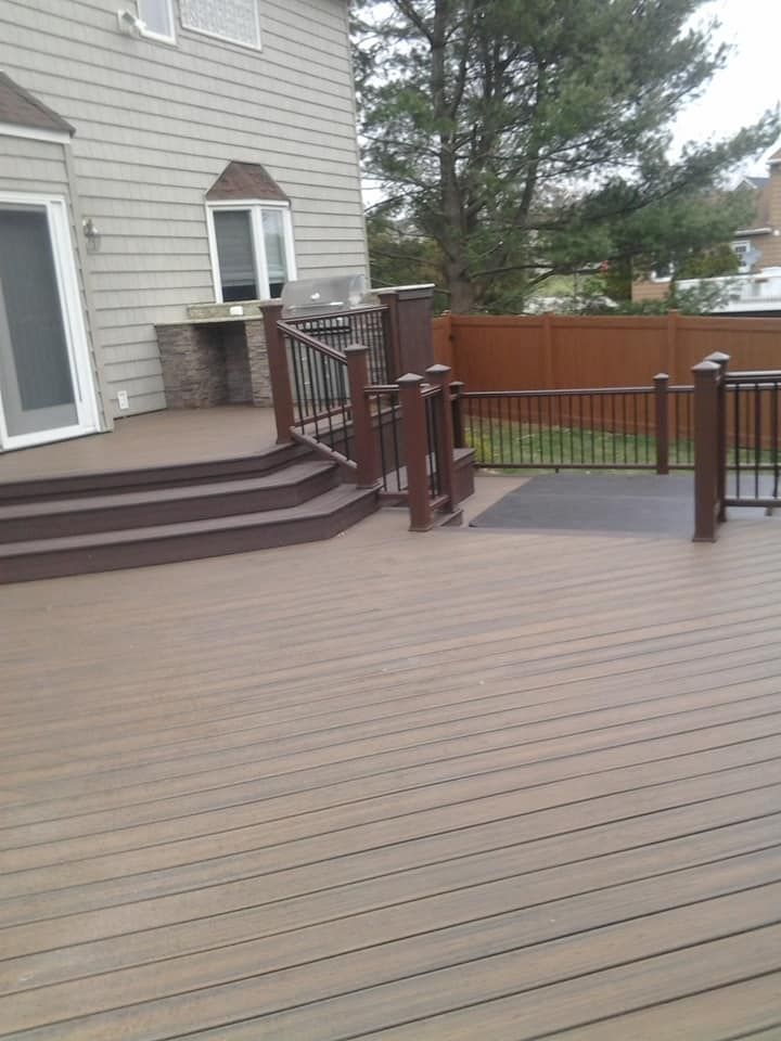 A wooden deck with stairs and a fence in front of a house.