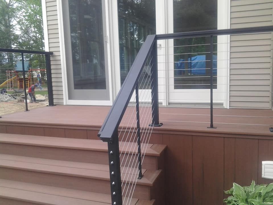 A wooden deck with stairs and a black railing